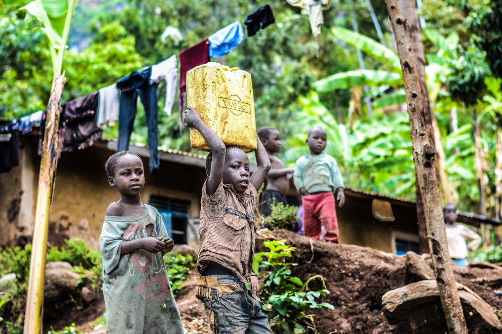 Two boys carrying water in a can which represents the significance of redistribution of water