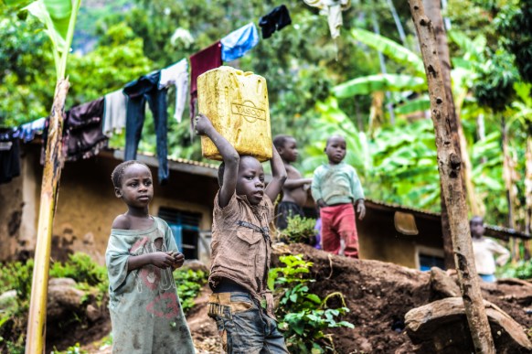 Two boys carrying water in a can which represents the significance of redistribution of water