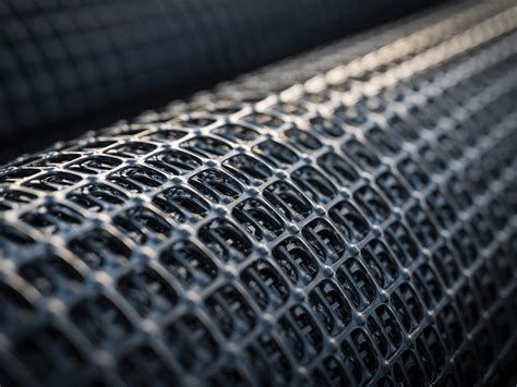 Close-up view of a black geogrid material, featuring a grid-like structure designed for soil reinforcement in civil engineering applications.