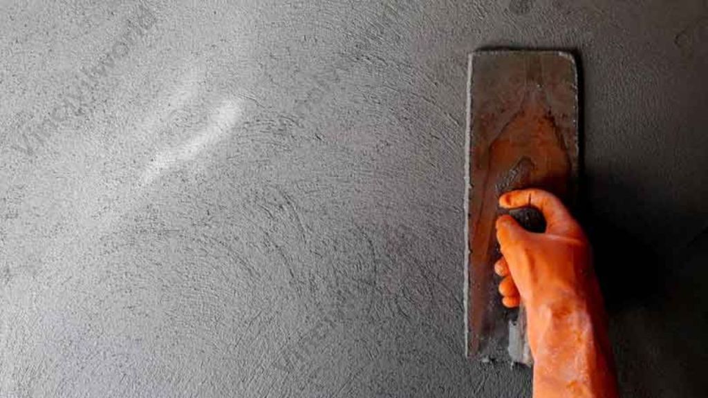A worker applying plaster to a wall with a trowel, showcasing the smooth finish of ready mix plaster.