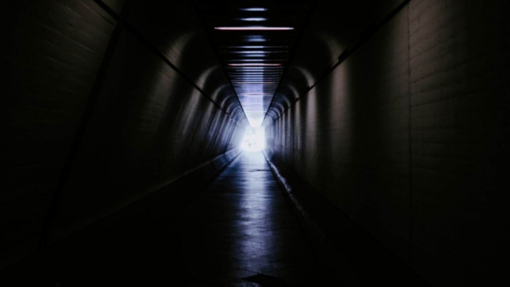 A perspective view of a long, dark tunnel with a bright light at the end, illustrating the concept of tunnel engineering.