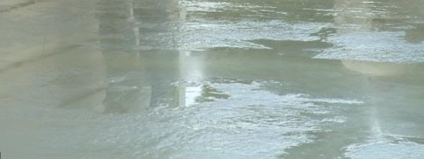 Surface of freshly poured concrete showing water accumulation due to bleeding.