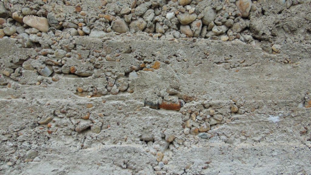 Close-up view of concrete with visible aggregates, showcasing uneven distribution of materials, indicating potential segregation.