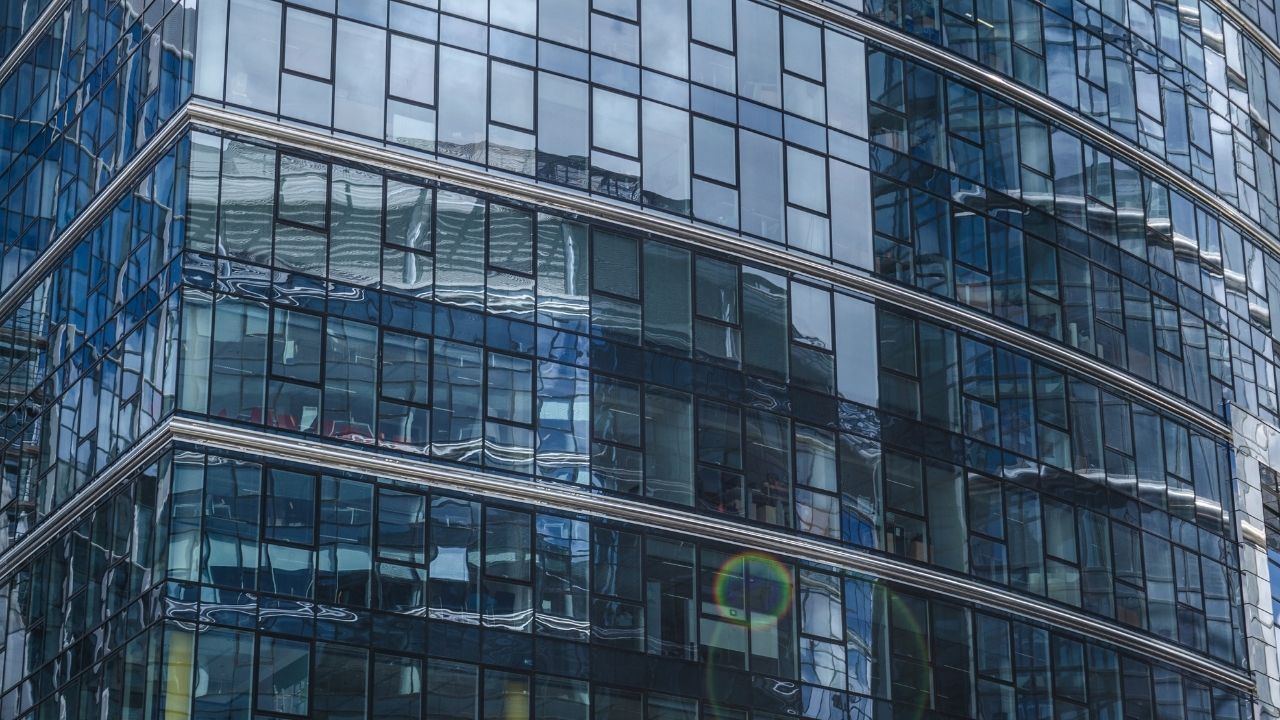 Close-up view of a modern building facade featuring large reflective glass windows with varying designs and textures.