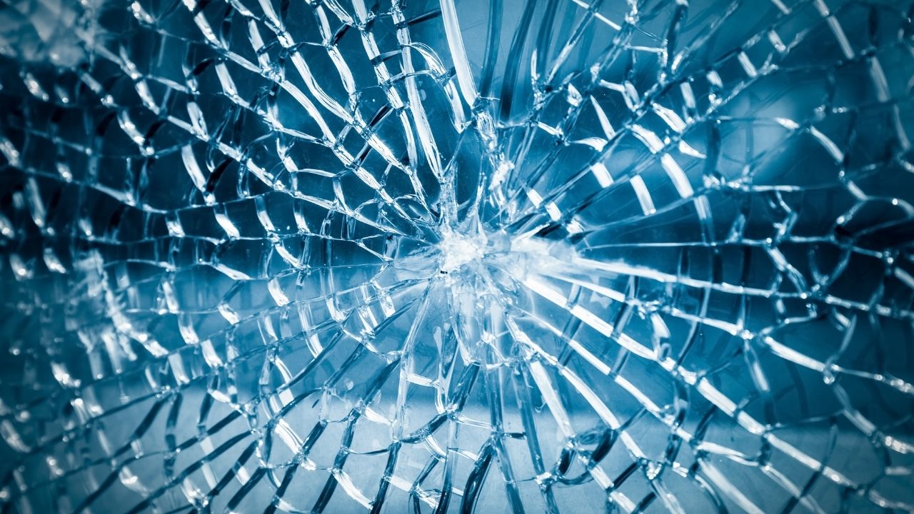 Close-up of shattered glass displaying a complex pattern of cracks.