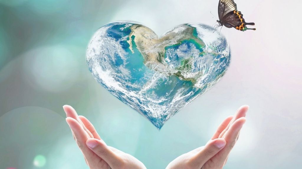A pair of hands gently cradling a heart-shaped globe depicting Earth, with a butterfly hovering above, symbolizing love and care for the planet.