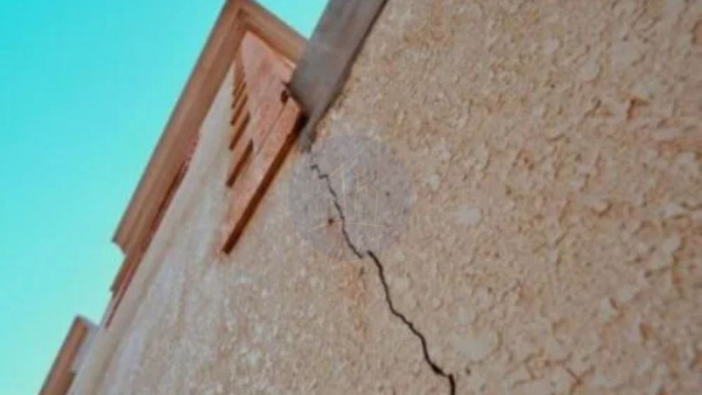 Close-up of a significant crack in the exterior wall of a building, indicating potential structural issues.