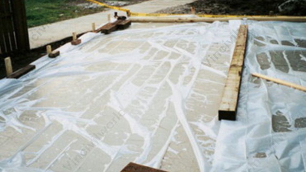 Concrete surface covered with plastic sheets for membrane curing to retain moisture and reduce evaporation.